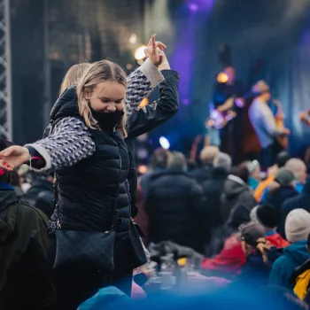 en person i svart frakk som danser foran en folkemengde