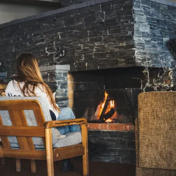 a person sitting in a chair by a fireplace