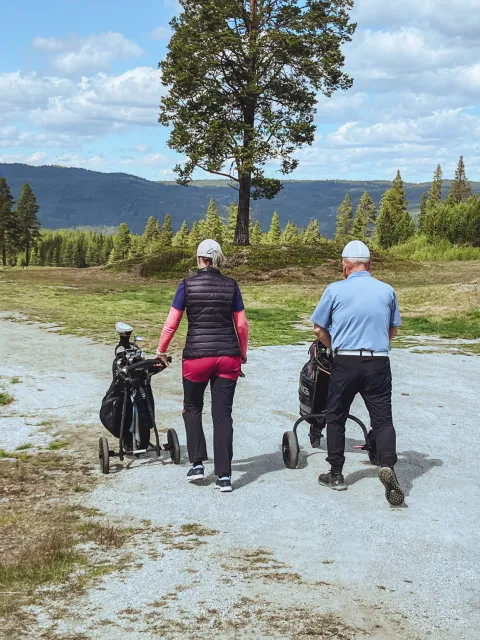 en person og person som går med golfkøller