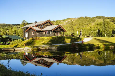 Nesfjellet Golf Kafé i solnedgang med tjern i forgrunn