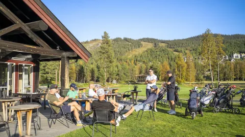 Gjester nyter solen utenfor Nesfjellet Golf Kafé