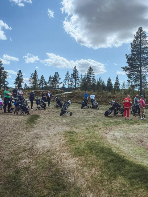En gruppe mennesker som står på et jorde med golfbiler